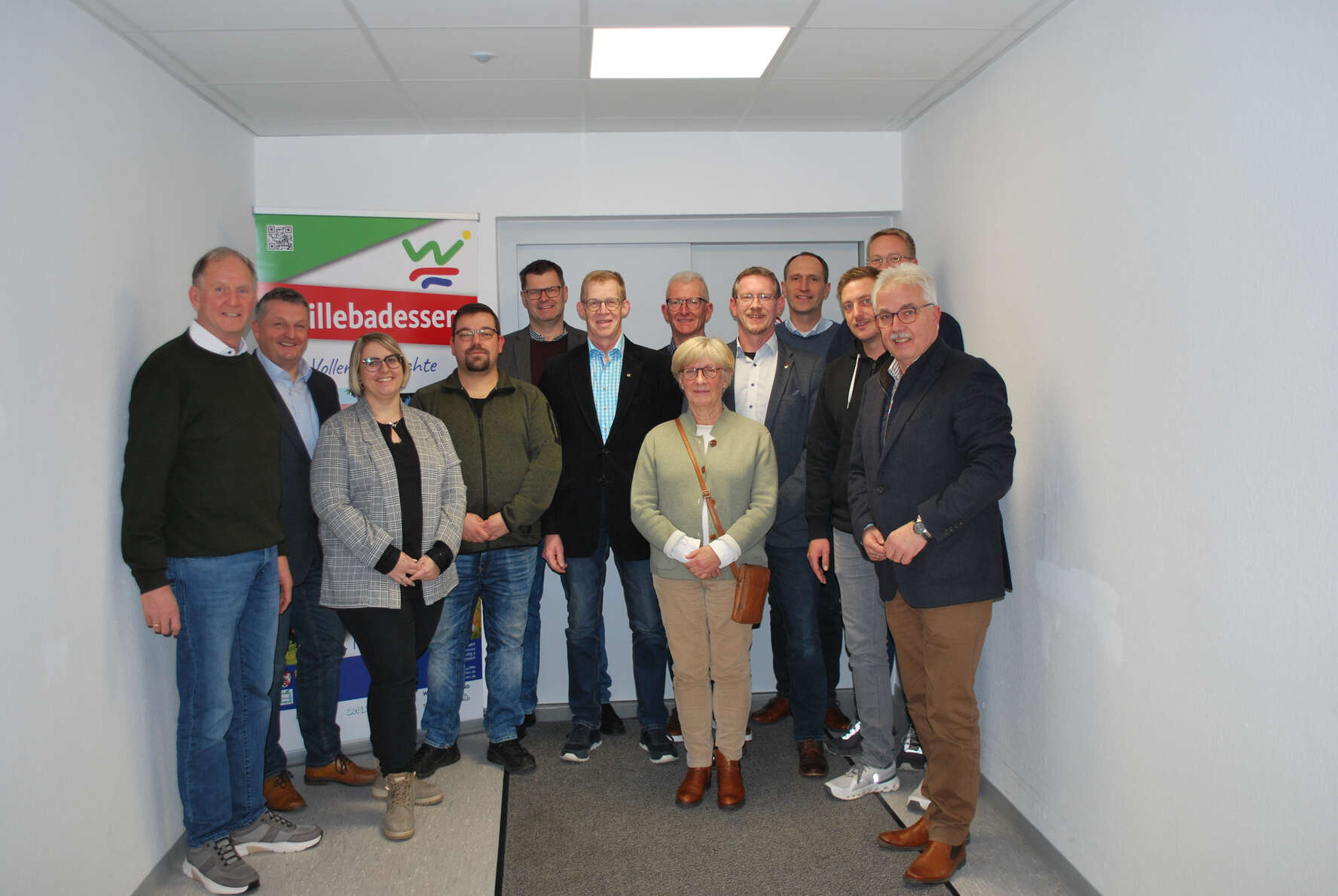 Menschen stehen im Flur einer Verwaltung vor einem Banner.