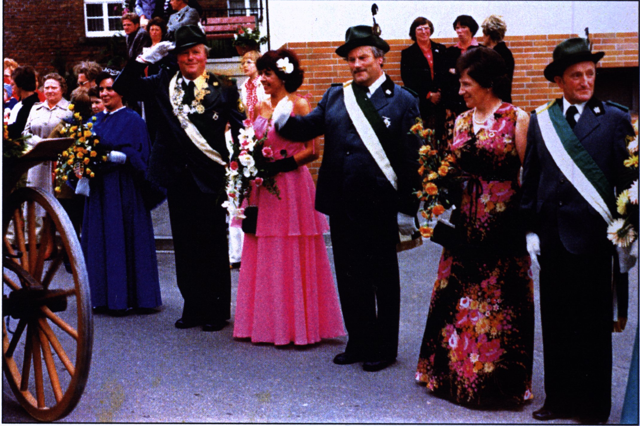 Schützenkönig mit Teilen ihres Hofstaats beim Abnehmen der Parade. Die Männer in grüner Uniform, die Frauen in festlichen Kleidern.